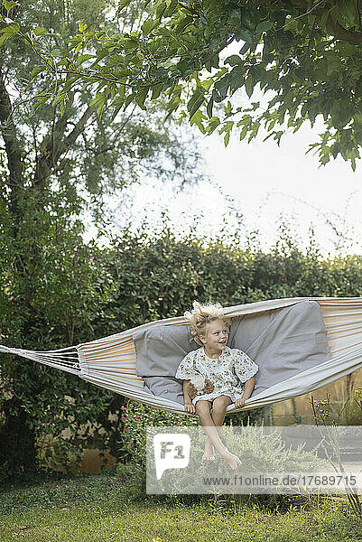 Playful girl swinging in hammock at garden
