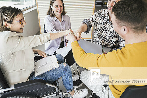 Business team touching fists in office