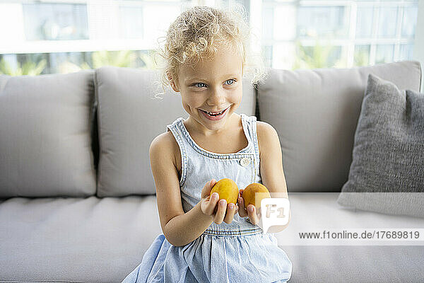 Happy girl with Easter eggs sitting on sofa at home