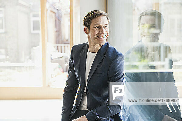 Smiling businessman looking out of window in office