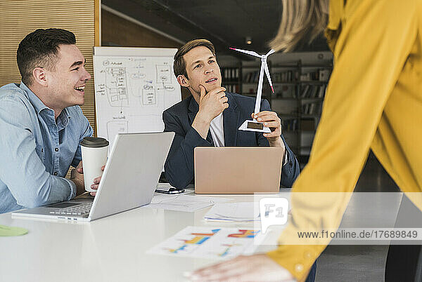 Business team with wind turbine model having a meeting in office