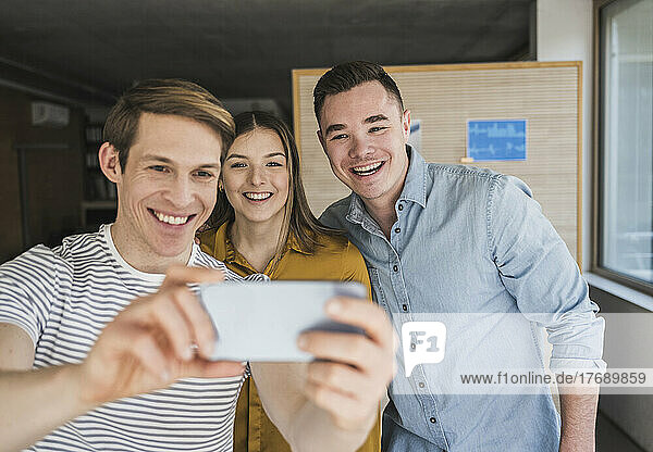 Happy business people taking a selfie in office