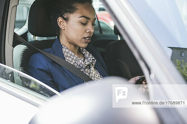 Businesswoman using smart phone sitting in car