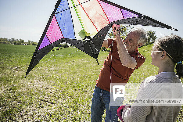 Großvater hilft Enkelin beim Drachensteigen auf dem Feld