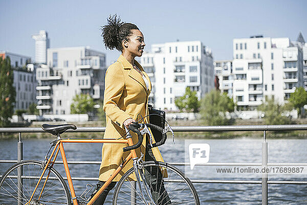Geschäftsfrau fährt an einem sonnigen Tag mit dem Fahrrad am Main entlang