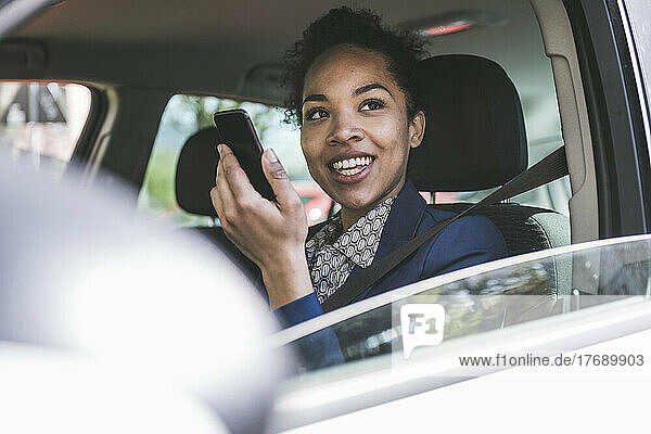 Happy businesswoman with mobile phone in car