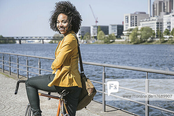 Smiling businesswoman with bicycle by River Main