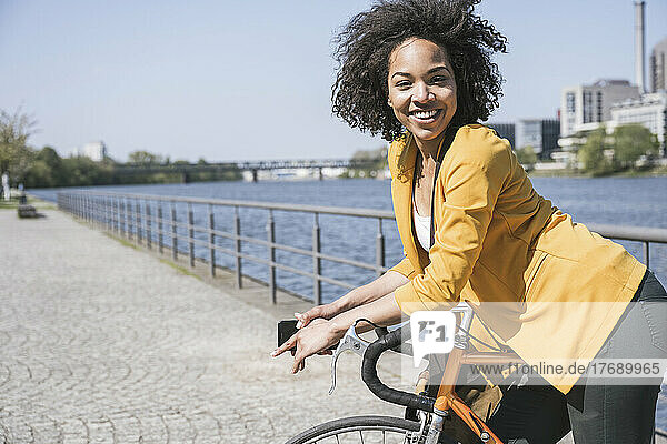 Happy commuter leaning on bicycle by River Main