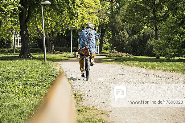 Senior man riding bicycle on footpath at park