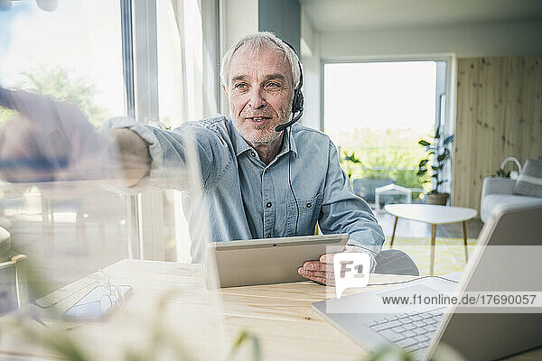 Freelancer wearing headset touching transparent screen at home