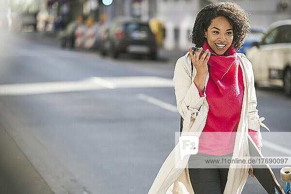 Smiling businesswoman using smart phone walking on street