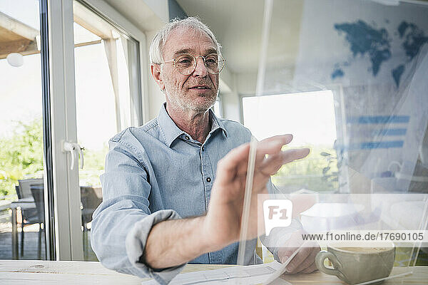 Senior businessman using glass screen at home