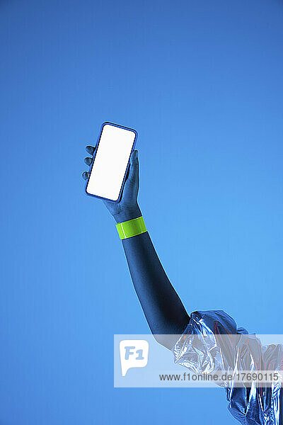 Hand of woman holding smart phone against blue background