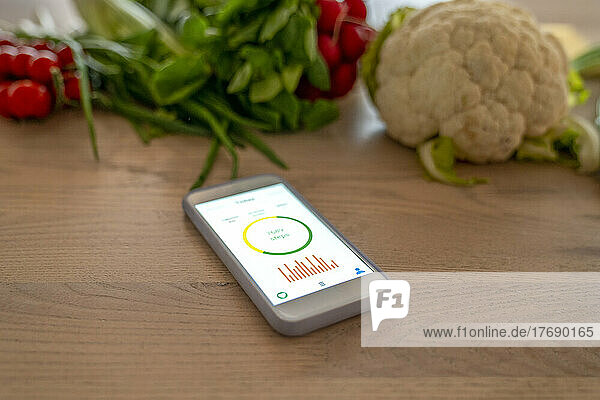 Smart phone with health tracker on device screen by vegetables