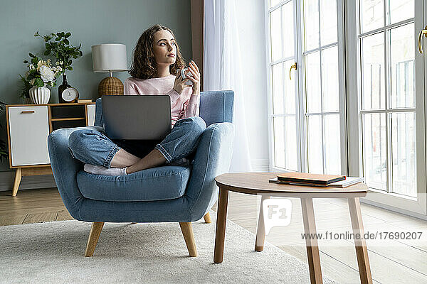 Thoughtful businesswoman with laptop at home