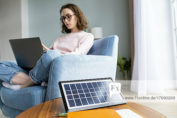Solar battery charger on table with businesswoman in background working at home