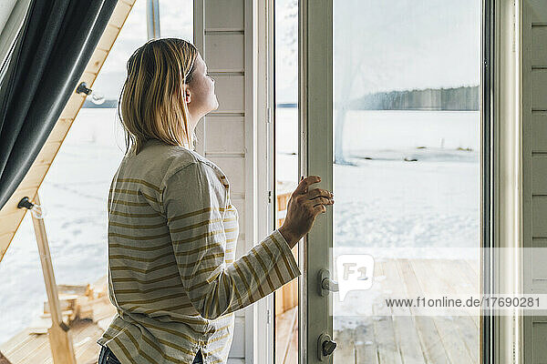 Frau atmet frische Luft durch Glastür zu Hause