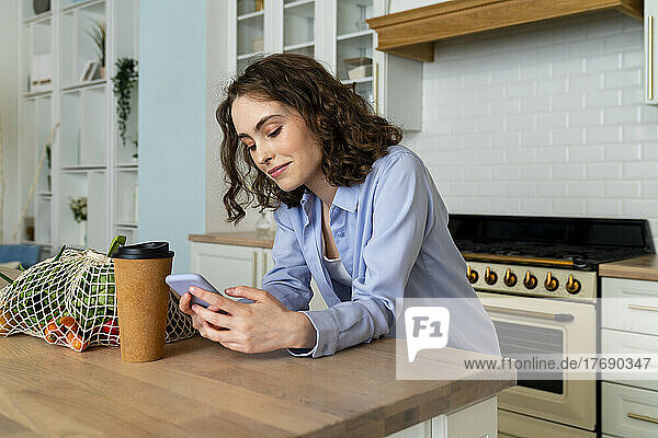Junge Frau benutzt Smartphone am Esstisch