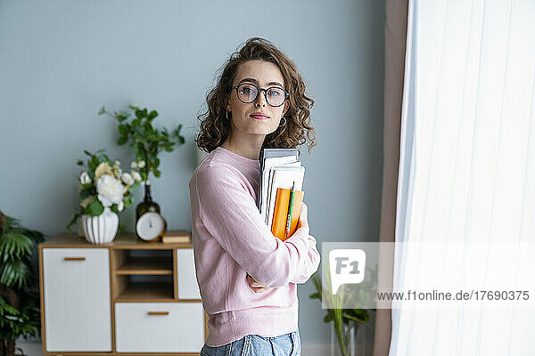 Young woman with book in living room at home