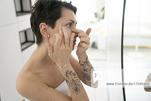 Woman applying eye mask in bathroom at home