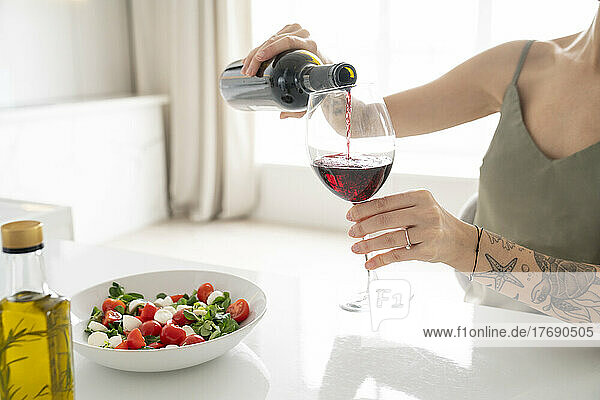 Woman pouring wine in glass at home