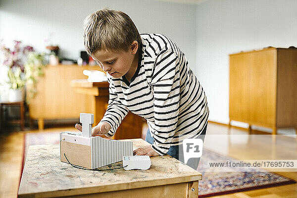 Boy with down syndrome using learning tool on table at home