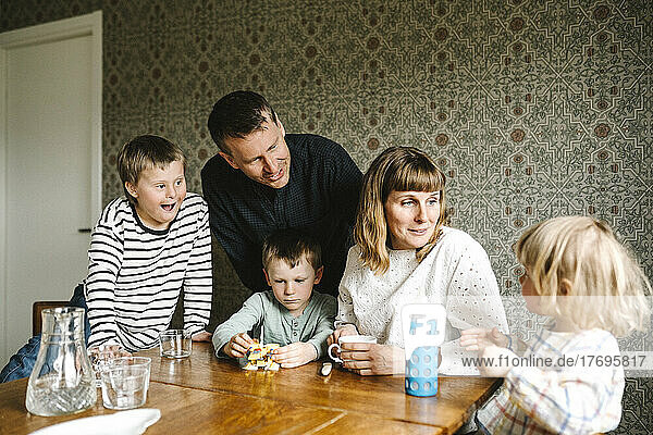Lächelnde Eltern im Gespräch mit Tochter und Söhnen am Tisch