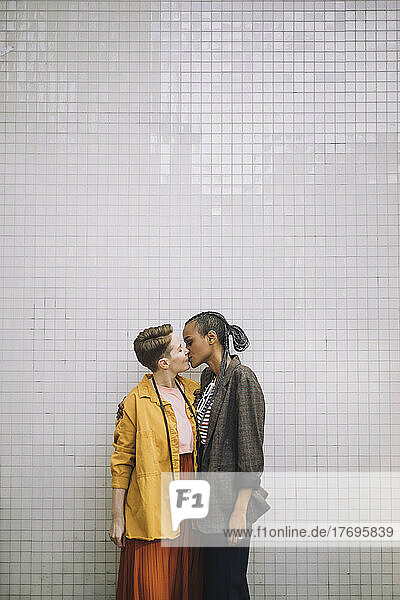 Zärtliches lesbisches Paar  das sich küsst  während es an der Wand steht