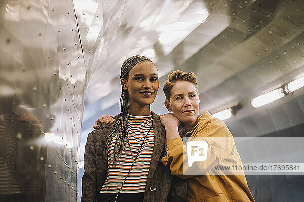 Porträt eines lächelnden lesbischen Paares  das in einem beleuchteten Tunnel steht