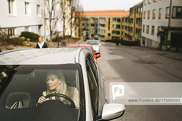 Geschäftsfrau im Auto sitzend durch die Windschutzscheibe gesehen