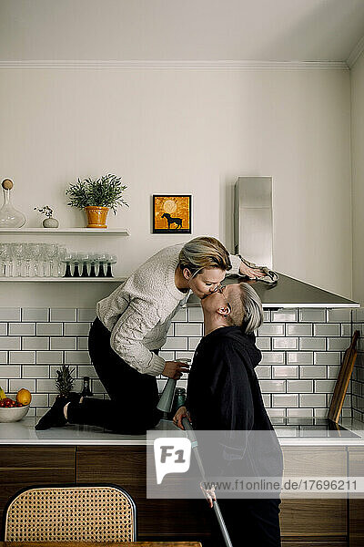 Zärtliche lesbische Frauen küssen sich beim gemeinsamen Putzen der Küche zu Hause