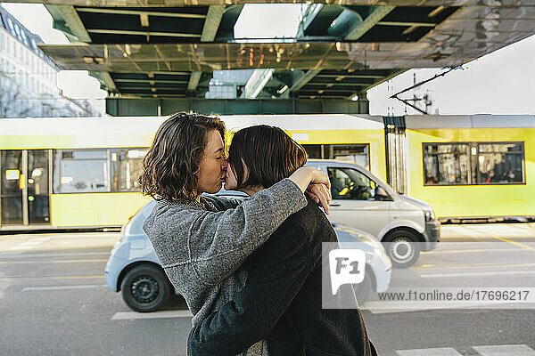 Lesbisches Paar  das sich küsst  während es auf der Straße unter einer Brücke in der Stadt steht