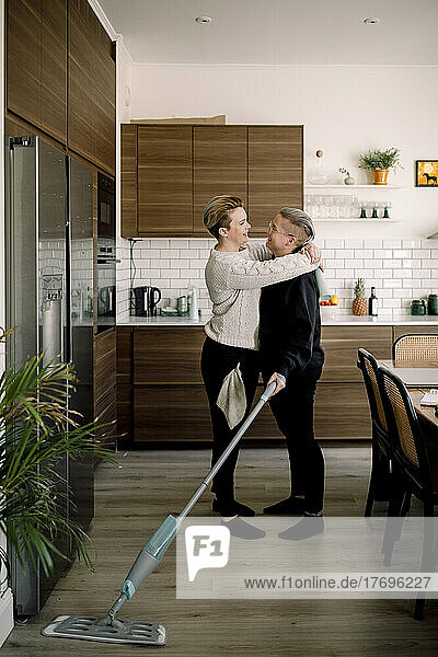 Seitenansicht eines romantischen lesbischen Paares  das sich bei der Hausarbeit gegenseitig umarmt