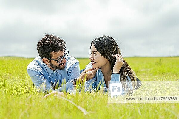 Junges verliebtes Paar  das im Gras liegt und sich gegenseitig berührt  zwei verliebte Menschen  die im Gras liegen und sich ansehen  Ein Paar  das im Gras liegt und sich ansieht