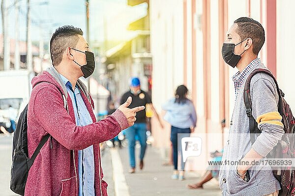 Two young people with mask having a conversation outdoors  two friends with face mask having a conversation  concept of conversation and social distance