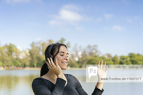 Junge Frau hört Musik im Freien mit Bluetooth-Kopfhörern. Ausdruck von Glück  gewinnende Einstellung. Textfreiraum