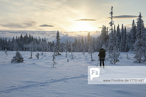 Woman hiking in snow at sunset