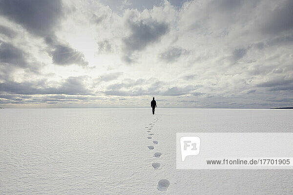 Footprints behind woman walking in snow