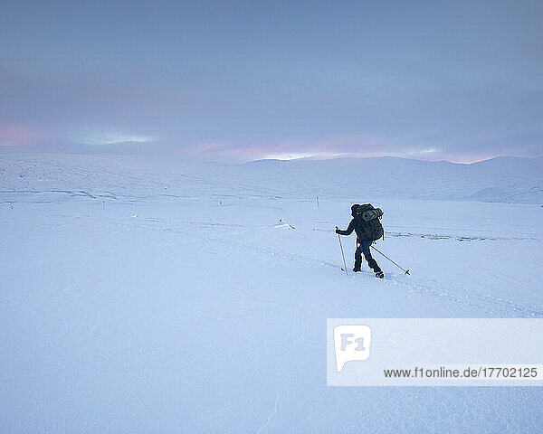 Young woman with hiking poles in snowy field