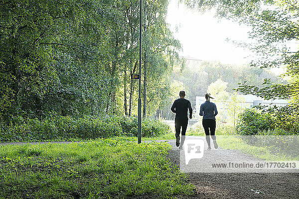 Man and woman jogging on trail in forest