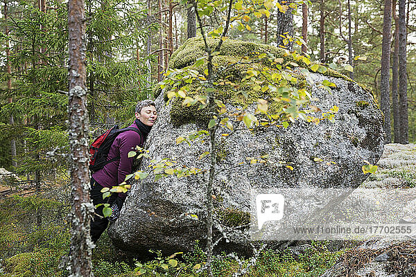 Woman leaning on rock in forest