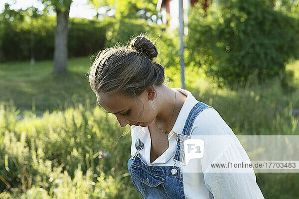 Young woman wearing blouse and overalls in field