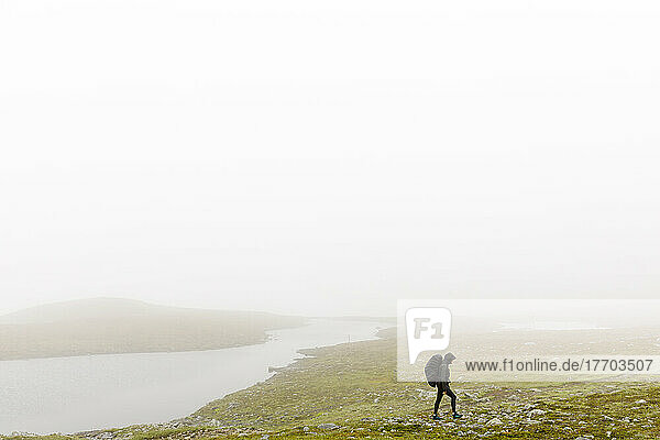 Woman with backpack hiking in fog