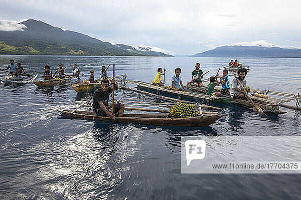 Islanders in outrigger canoes selling tropical fruits off Dobu in the Solomon Sea; Dobu  D'Entrecasteaux Islands  Papua New Guinea