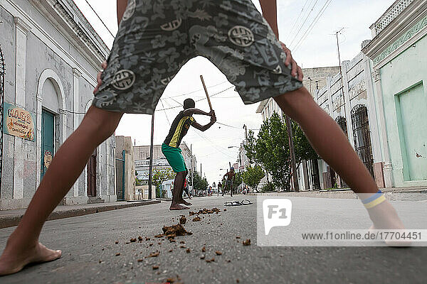 Several young men play baseball in the streets of Cienfuegos.; Cienfuegos  Cuba