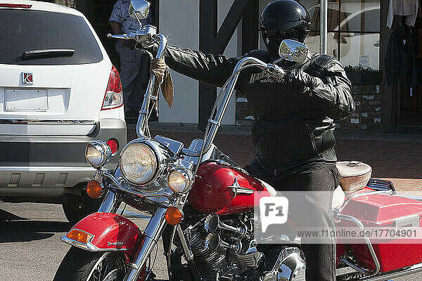 Ein schwarz gekleideter Motorradfahrer auf einem roten Motorrad; Kalifornien  Vereinigte Staaten von Amerika
