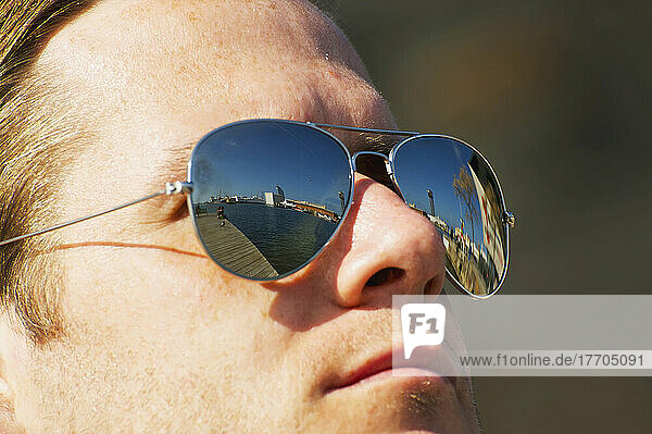 Ein Mann trägt eine Sonnenbrille  in deren Gläsern sich die Promenade spiegelt; Barcelona  Spanien