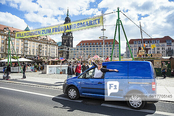 Frau hängt mit ausgestreckten Armen aus dem Autofenster und freut sich auf dem Altmarkt über ein Fest auf dem Dresdner Frühlingsmarkt; Dresden  Sachsen  Deutschland