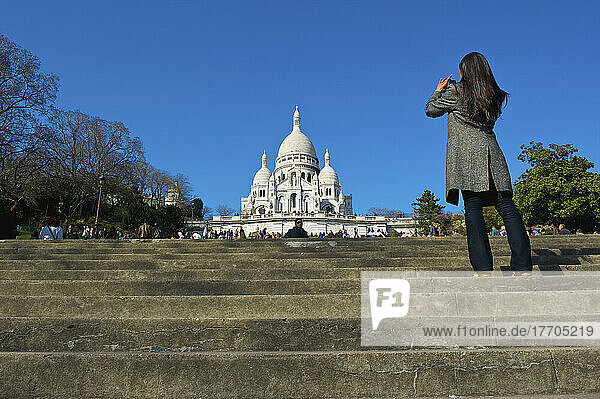 Tourist steht auf den Stufen und fotografiert die Basilika des Heiligen Herzens von Paris; Paris  Frankreich