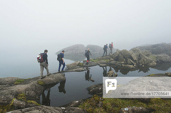 Hikers Walking Past Small Loch In The Mist Below Sgurr Alasdair In The Black Cuillins; Isle Of Skye  Scotland